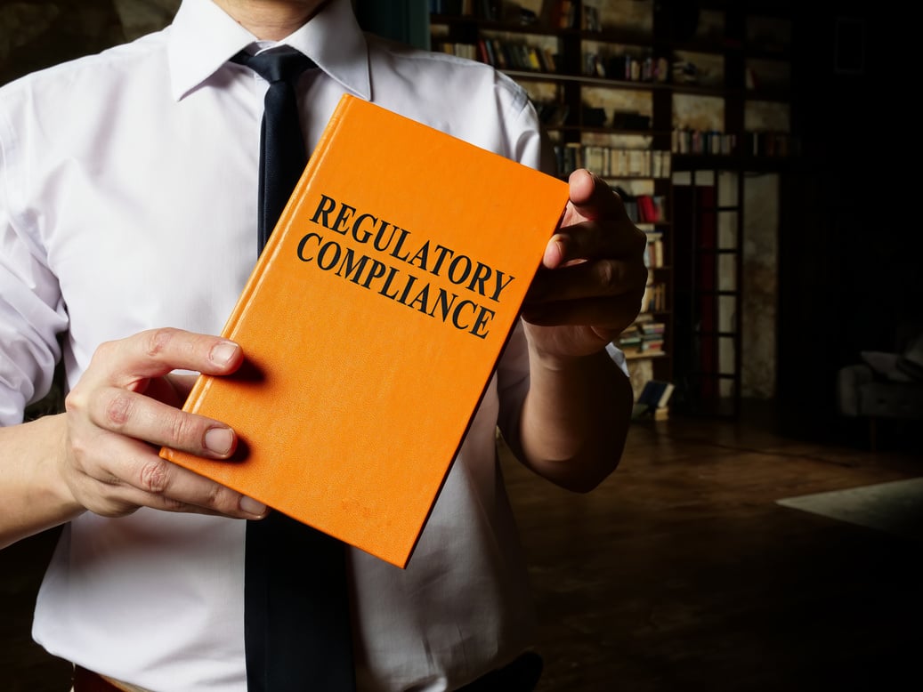 Regulatory compliance book in the hands of a man with a tie.