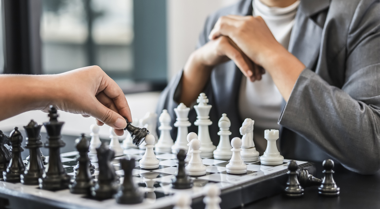 Two business women competitors playing chess board game, business competition concept, business plan to be the number one company, competitor analysis and problem solving. For always good results.