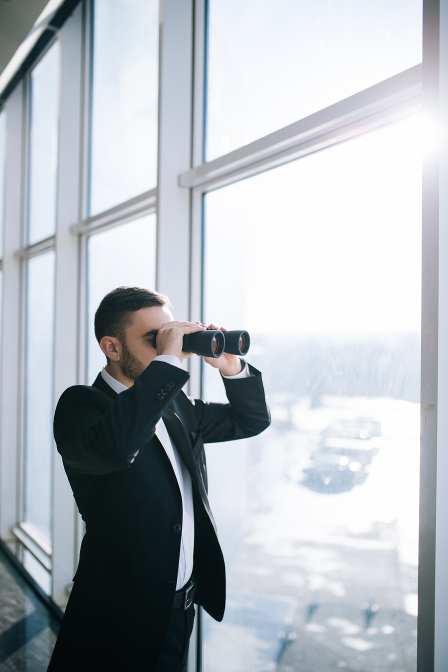 Businessman with binoculars spying on competitors.